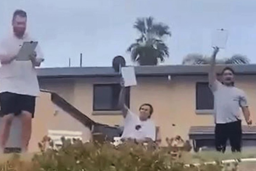 Three men holding up whiteboards