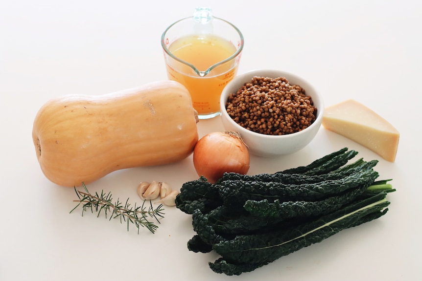 Butternut pumpkin, brown onion, tinned lentils and dinosaur kale, soup ingredients on a kitchen bench.