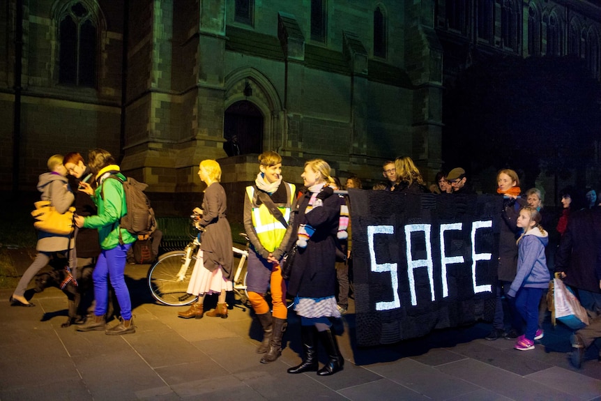 A group of woman out night on the street with a knitted banner with the words "safe"