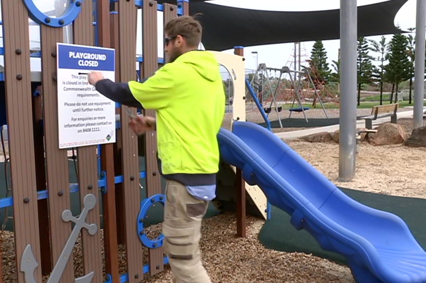 A council worker cuts down a sign on a playground