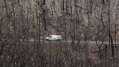 A car drives through a landscape devastated by bushfires in February near the township of Kinglake