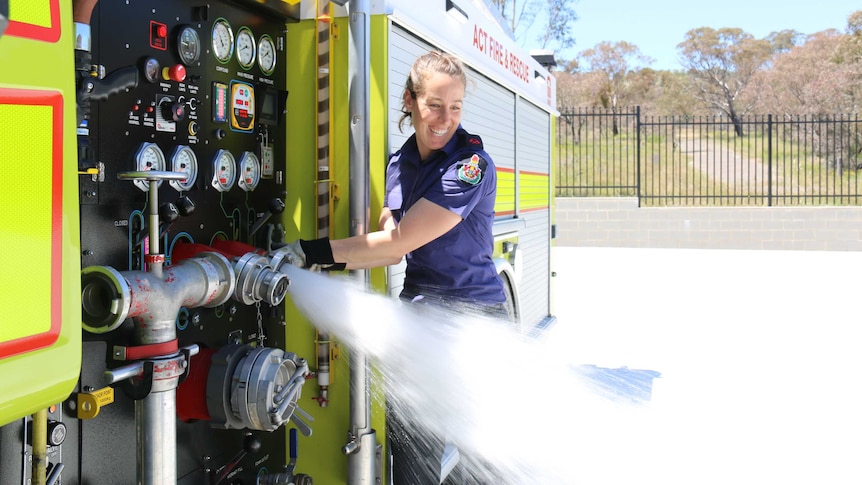 ACT firefighter Danni Curcio tests the water pressure of the hose on the fire engine.