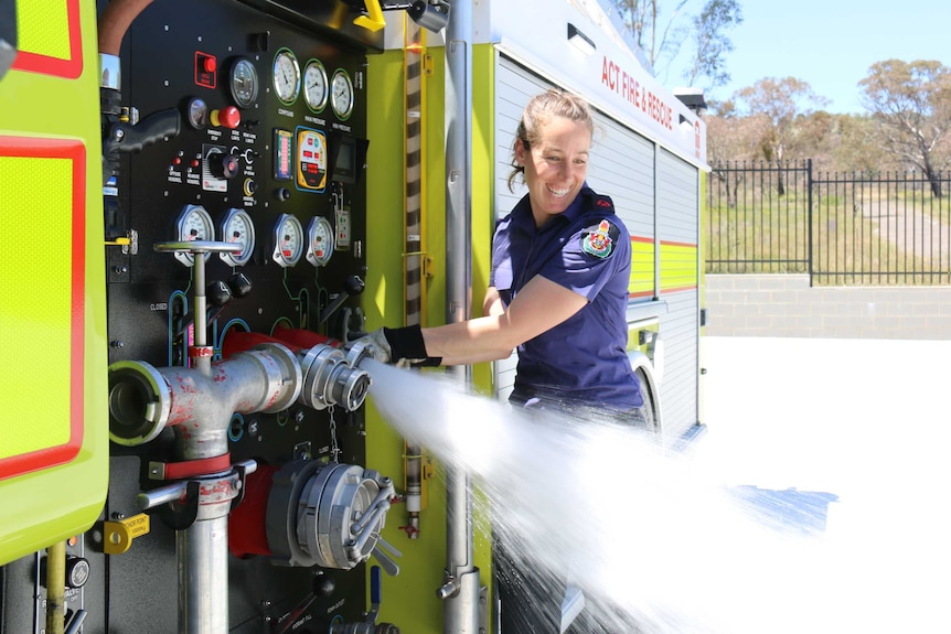 ACT firefighter Danni Curcio tests the water pressure of the hose on the fire engine.