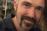 A selfie of a man with a goatee beard wearing a navy shirt.