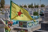 A Kurdish flag flies on top of a tomb stone.