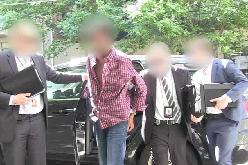 Police lead a Werribee man in handcuffs out of an unmarked police car.