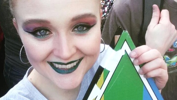 Young woman holding a Greens rainbow sign.