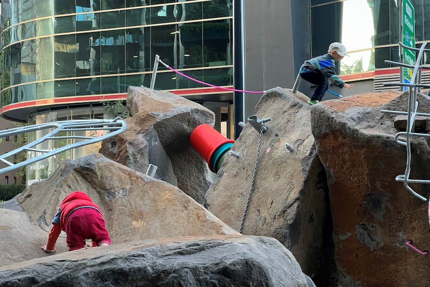 A photo of large rocks with two small children playing on top of them