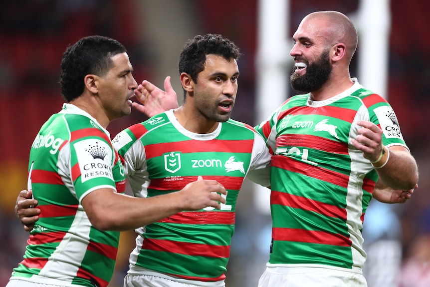 Three South Sydney NRL players embrace as they celebrate a try scored against the Roosters.