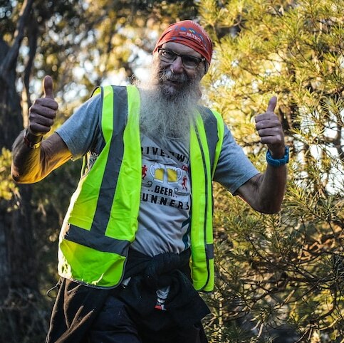 Ross Johnston in the bush smiling and holding up two thumbs.