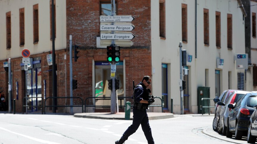 French policeman runs in front of the scene of a hostage siege