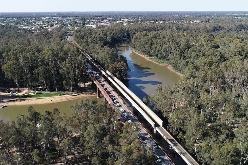 from the sky, you can see a bridge across a river, cars and trucks line up on the left hand lane waiting to cross the river