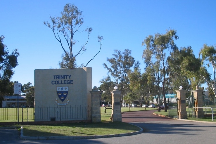 A wide shot showing the gates at the entrance to Trinity College in Perth with the school insignia on a brick wall.