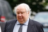 Sergei Kislyak looks just past the camera. He is wearing a suit with a blue shirt and dark tie.