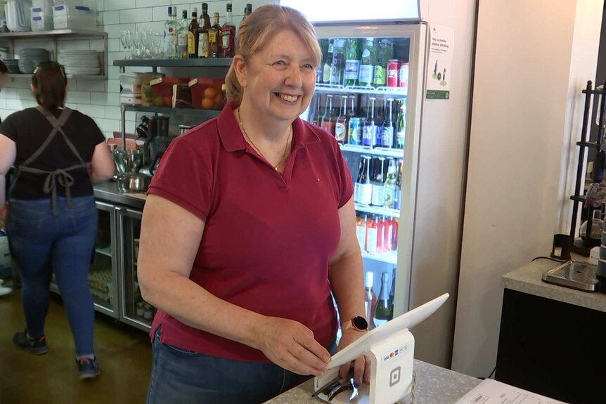 A woman behind a cafe counter smiles