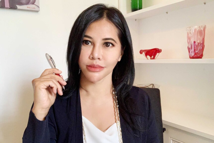 A picture of an Indonesian woman wearing a blazer and holding a pen.