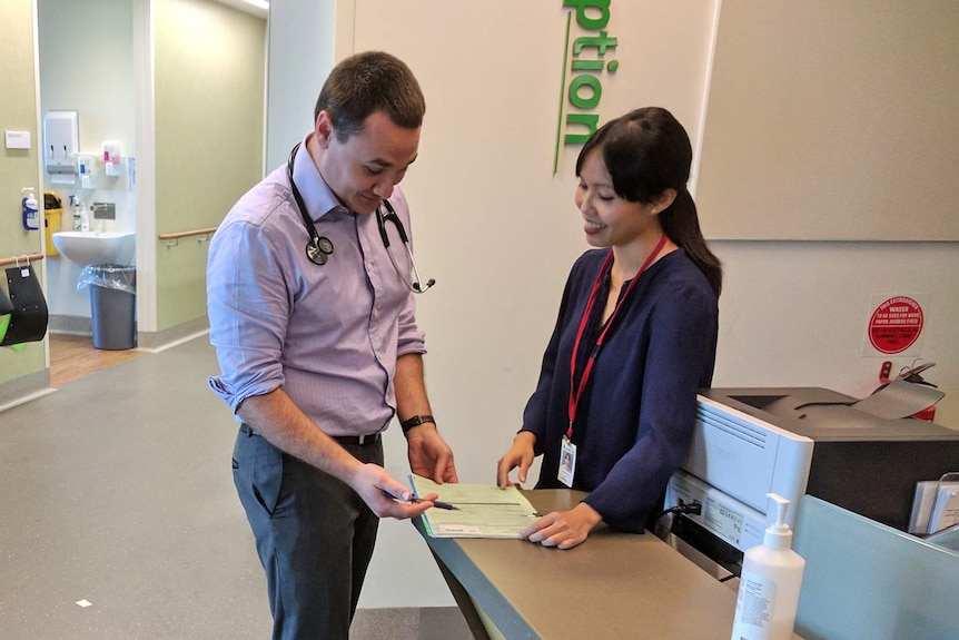 A male doctor points to paperwork held by a younger female doctor