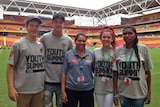 A group of four Indigenous teenagers stand with an older Indigenous woman at Suncorp Stadium