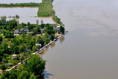An aerial view of a temporary levee holding back floodwater that is threatening homes.