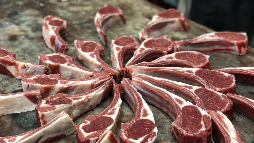 A display of raw lamb cutlets on bench laid out in a spiral.