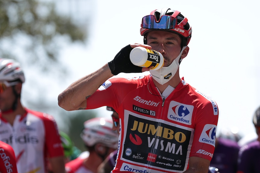 Primož Roglič has a drink wearing a red jersey