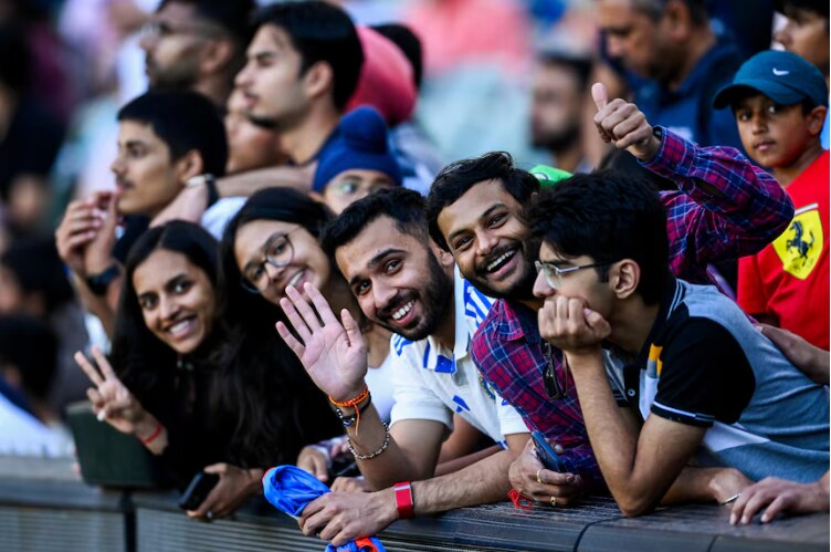 Indian cricket fans lean over the boundary smiling
