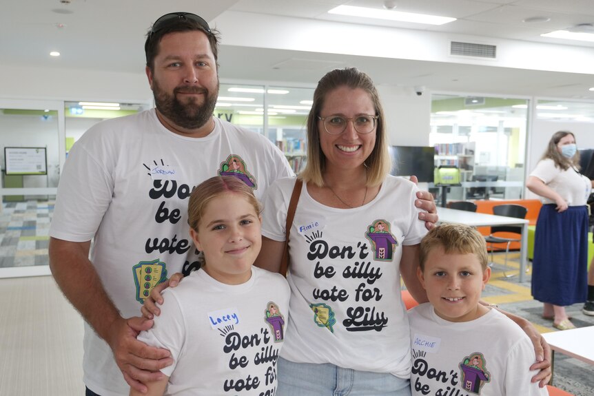 A family huddled together wearing T shirts with 'don't be silly, vote for Lily' printed on them. 