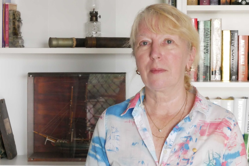 Woman looks at camera, books in background