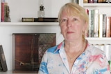 Woman looks at camera, books in background