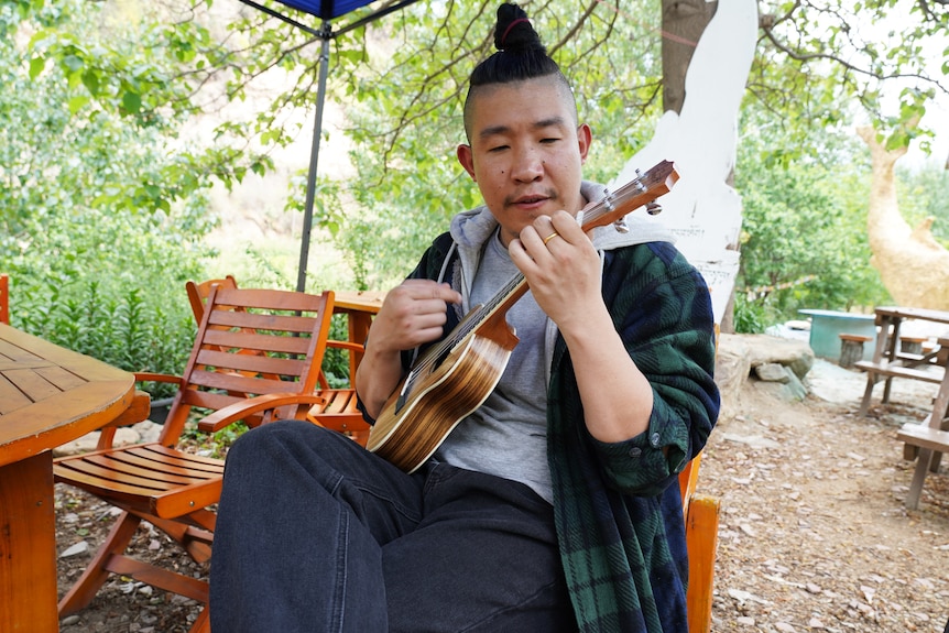 A young man with his hair tied into a bun on his head 