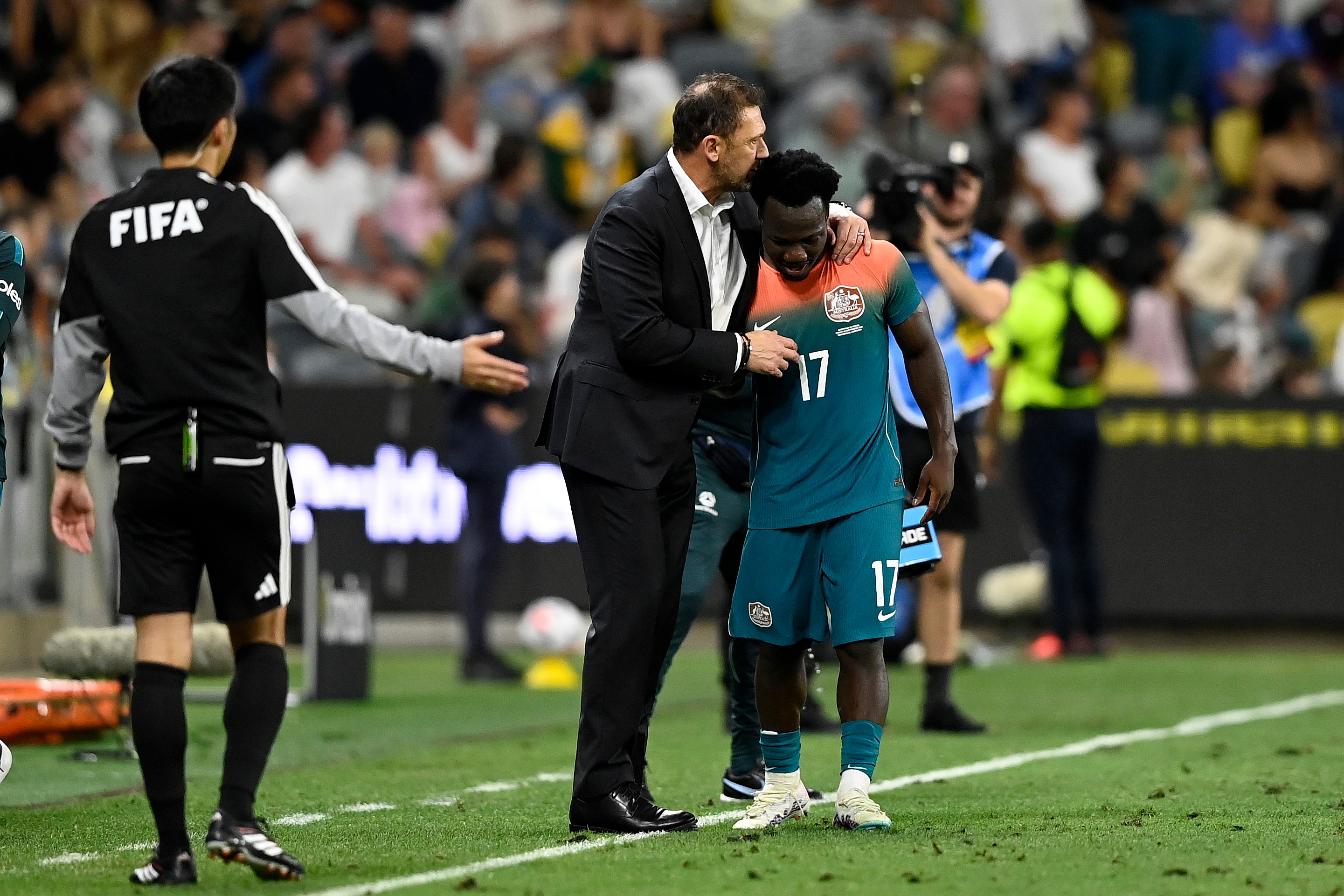 Coach Tony Popovic hugs player Nestory Irankunda on the soccer field. 