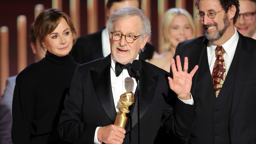 An man in a suit holding a trophy