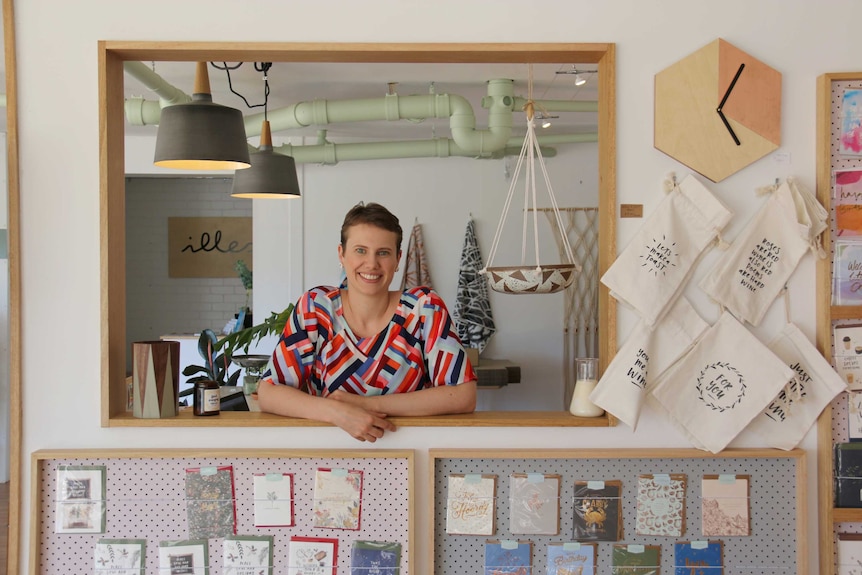 A woman stands in a gift shop surrounded by colourful objects.