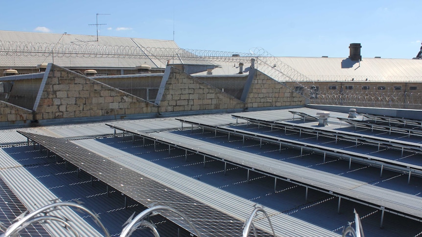 Solar panels sit on the roof of an old Victorian brick building