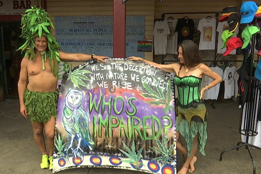 A  pair of scantily-clad marijuana advocates hold up a sign that reads 'who's impaired?'