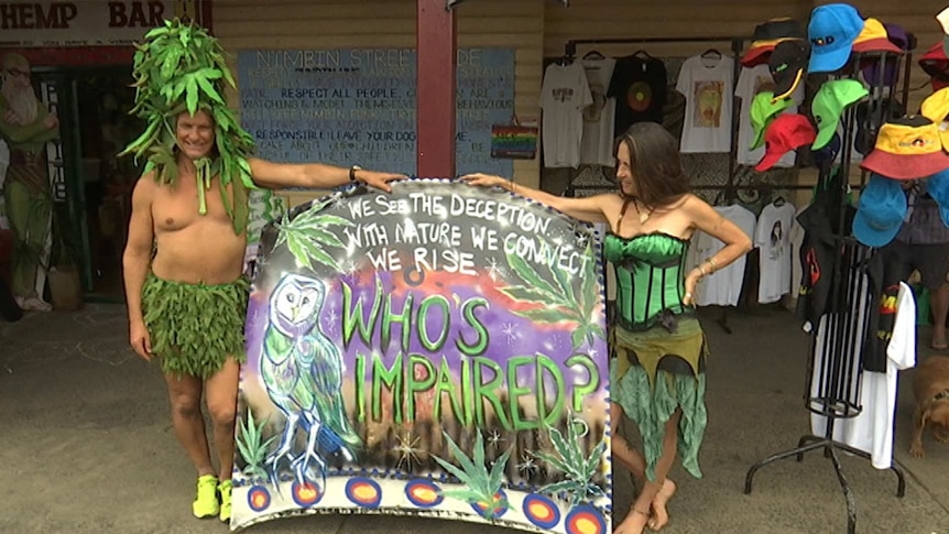 A  pair of scantily-clad marijuana advocates hold up a sign that reads 'who's impaired?'