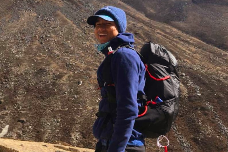 A hiker in front of a mountain.