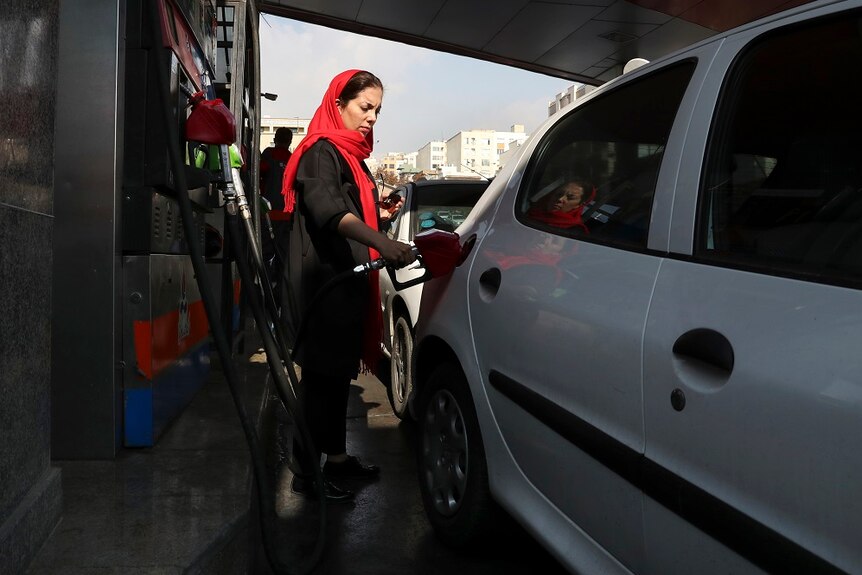 A woman getting petrol at a petrol station in Iran.