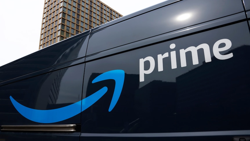 The side of a black Amazon Prime delivery vehicle, with a blue arrrow and the word "Prime" in white, shot from a low angle