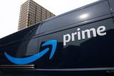 The side of a black Amazon Prime delivery vehicle, with a blue arrrow and the word "Prime" in white, shot from a low angle