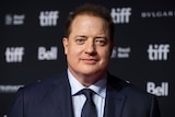 brendan fraser in a blue suit poses on the red carpet