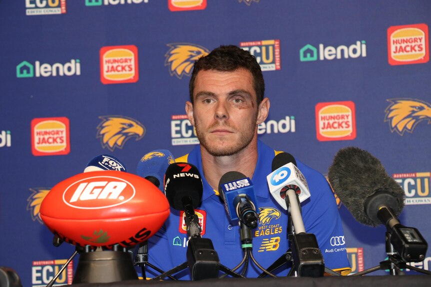Luke Shuey has bruises on his face as he addresses media with a despondent expression