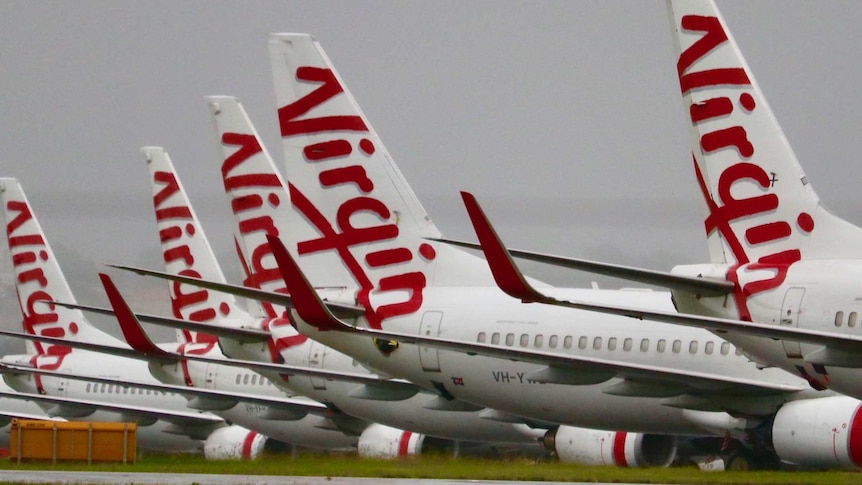 Photo showing Virgin jets parked on a runway.