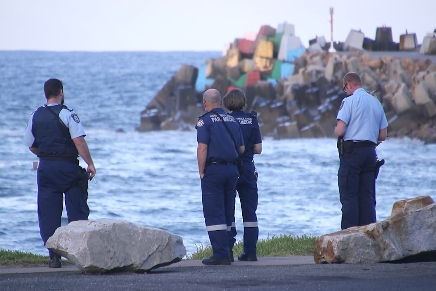 Police officers standing at the water's edge.