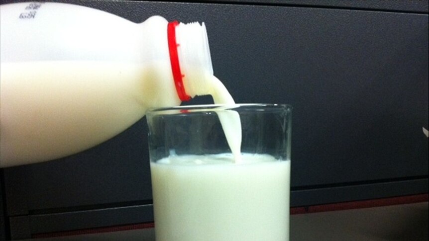 A glass of milk fills as a two litre bottle is poured by an invisible hand.