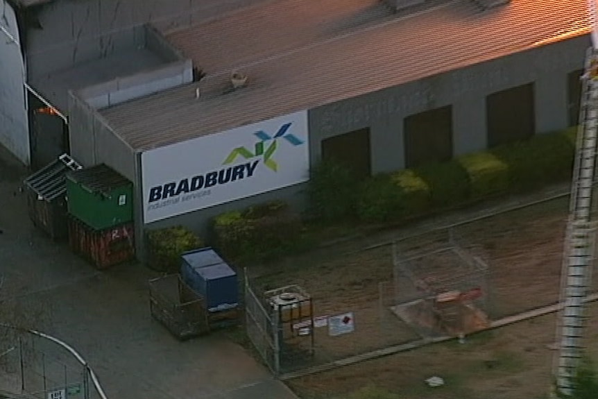A sign reading "Bradbury Industrial Services" is visible on the side of a building as orange flames glow nearby.