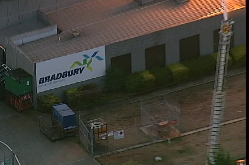 A sign reading "Bradbury Industrial Services" is visible on the side of a building as orange flames glow nearby.
