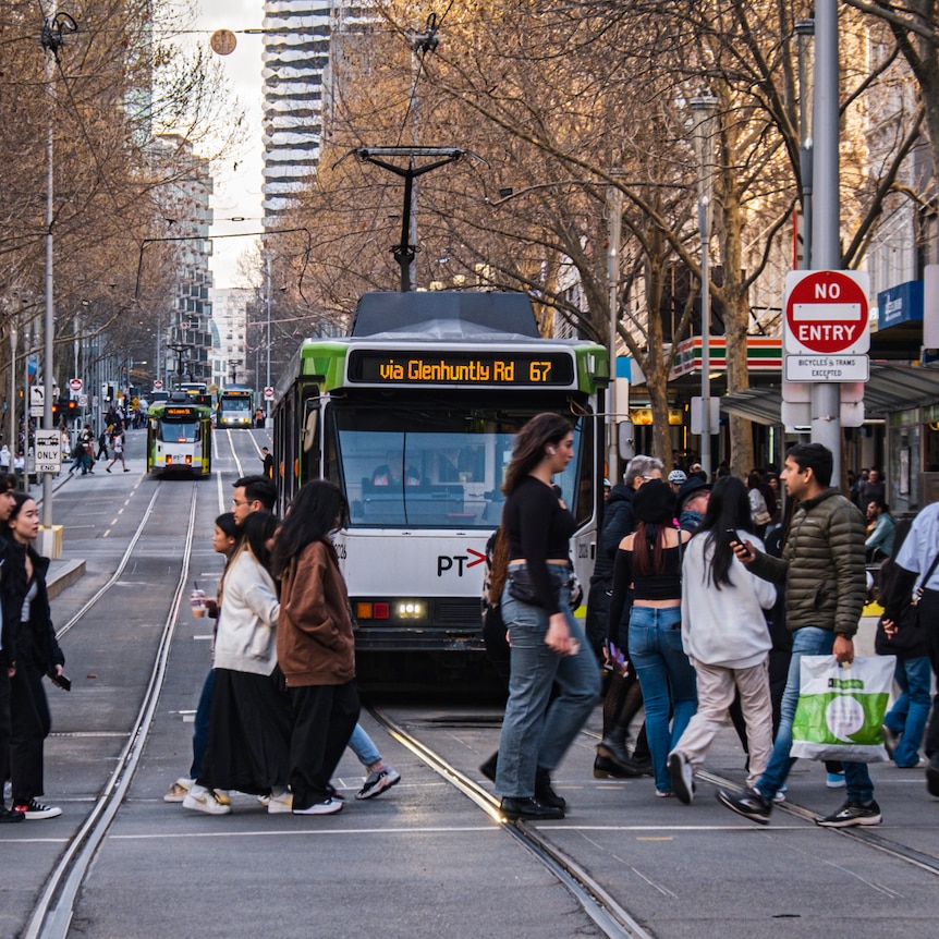 A shot of a busy Melbourne street with pedestrians in front of a tram.