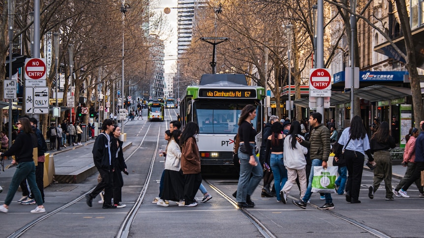 A shot of a busy Melbourne street with pedestrians in front of a tram.