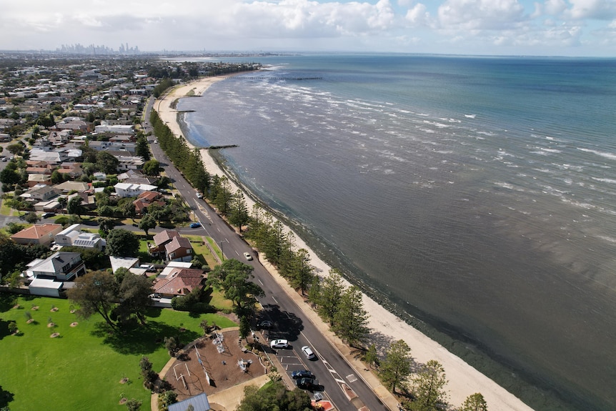 An aerial photo of Altona beach with houses on the left and a clear ocean on the right. 